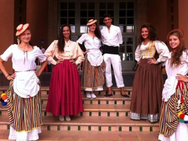 Praktikanten freuen sich, traditionelle kanarische Kleidung zu tragen Fröhliche Praktikanten tragen traditionelle kanarische Kleidung und zeigen Begeisterung.
