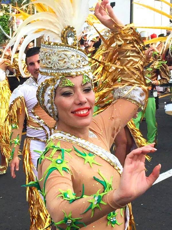 Una mujer hermosa baila con un disfraz dorado y verde brillante durante el desfile de carnaval Mujer hermosa bailando con un disfraz dorado y verde brillante en medio del desfile de carnaval.