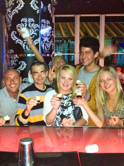 Los becarios se ríen en el bar después del trabajo Grupo de becarios riendo y disfrutando de bebidas juntos en un bar animado después del trabajo.