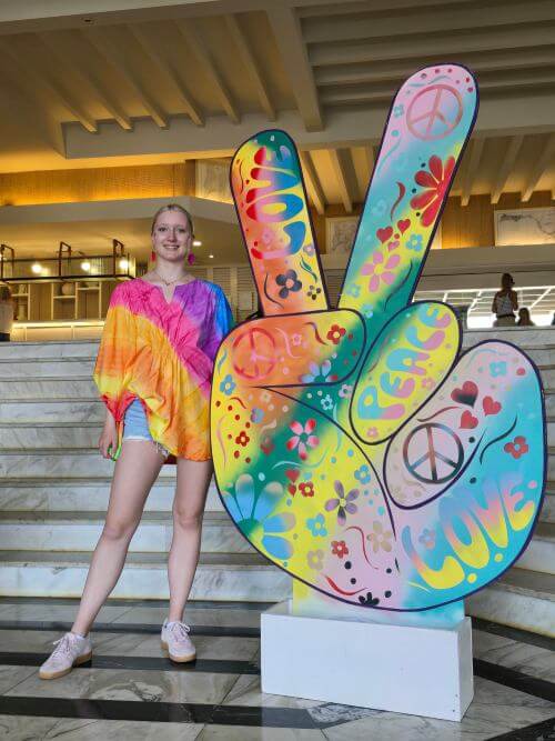Happy intern dressed up in costume standing in front of a large peace sign