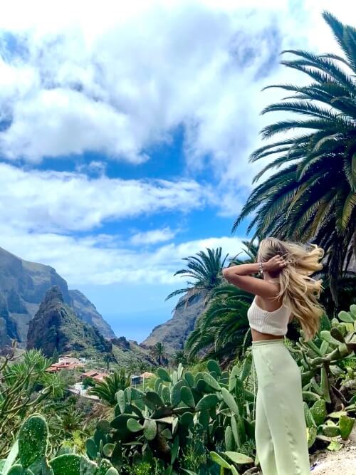 Praktikantin in Masca während ihres Praktikums Praktikantin steht vor der Kulisse des Bergdorfs Masca auf Teneriffa.