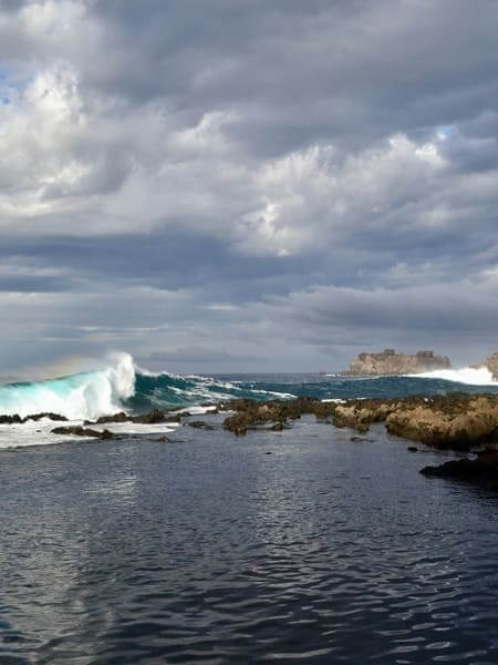 Costa selvaggia di El Hierro Costa atlantica selvaggia di El Hierro con onde che si infrangono, rocce vulcaniche e cielo nuvoloso drammatico.